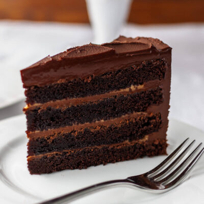 A slice of chocolate cake with caramel filling on a white plate.
