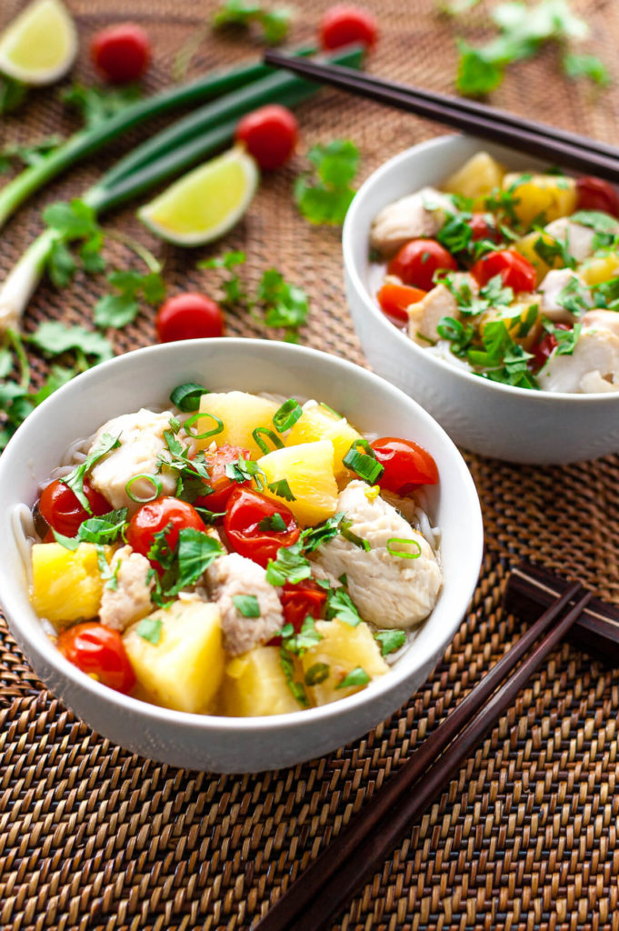 Two bowls of Vietnamese fish, pineapple, and tomato soup sprinkled with chopped green onions and cilantro.