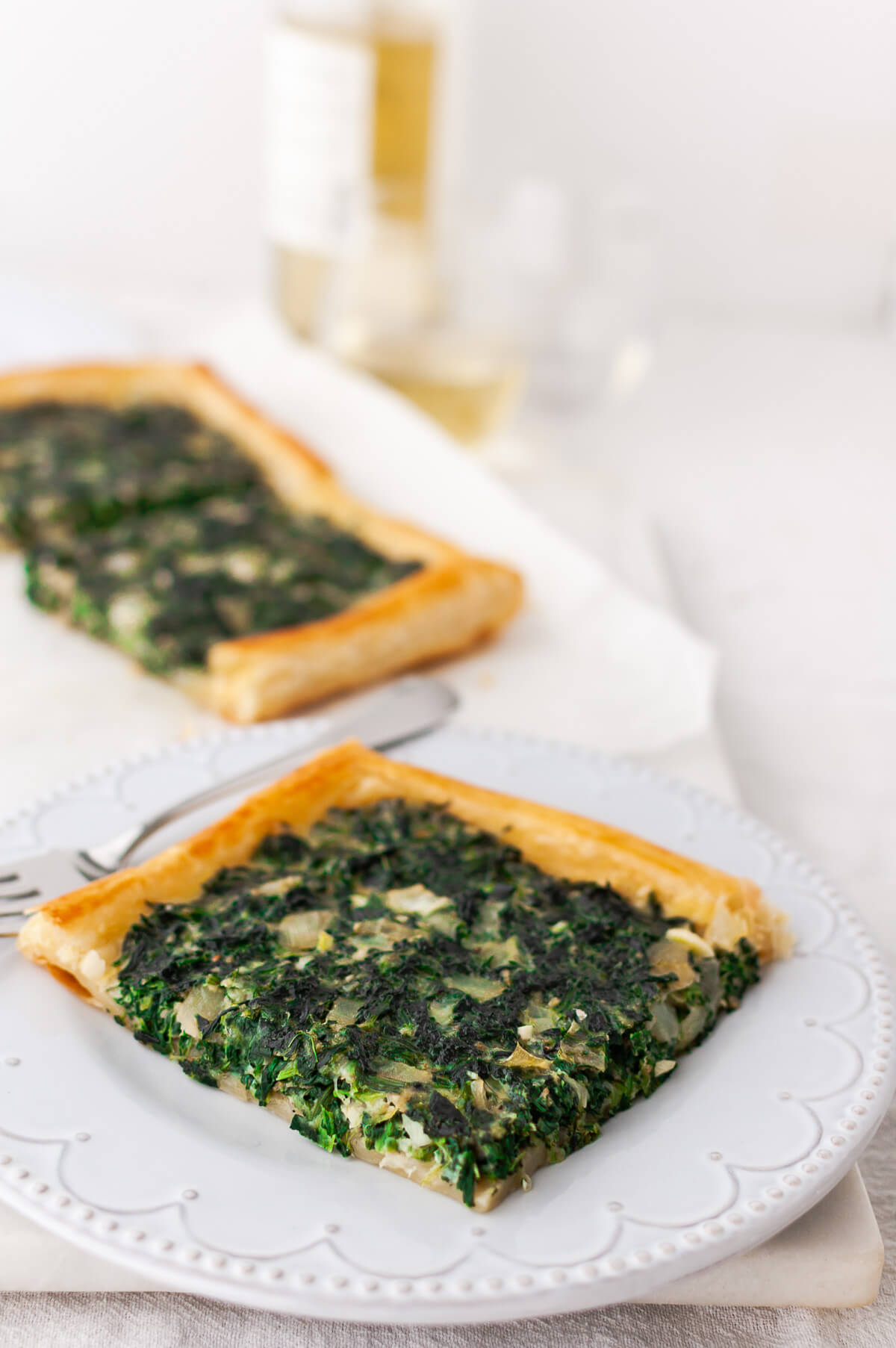 A piece of spinach tart on a white plate.