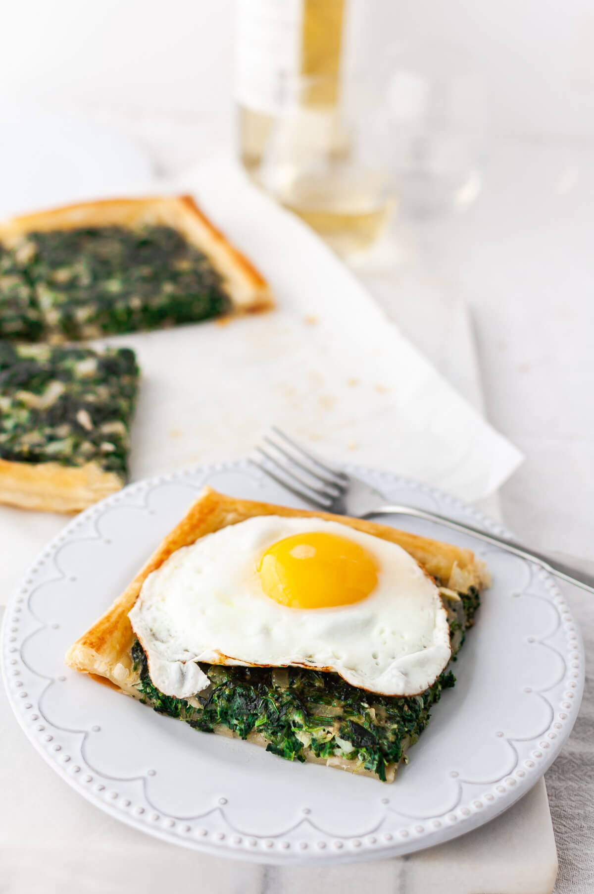 A slice of spinach tart with a fried egg on top.