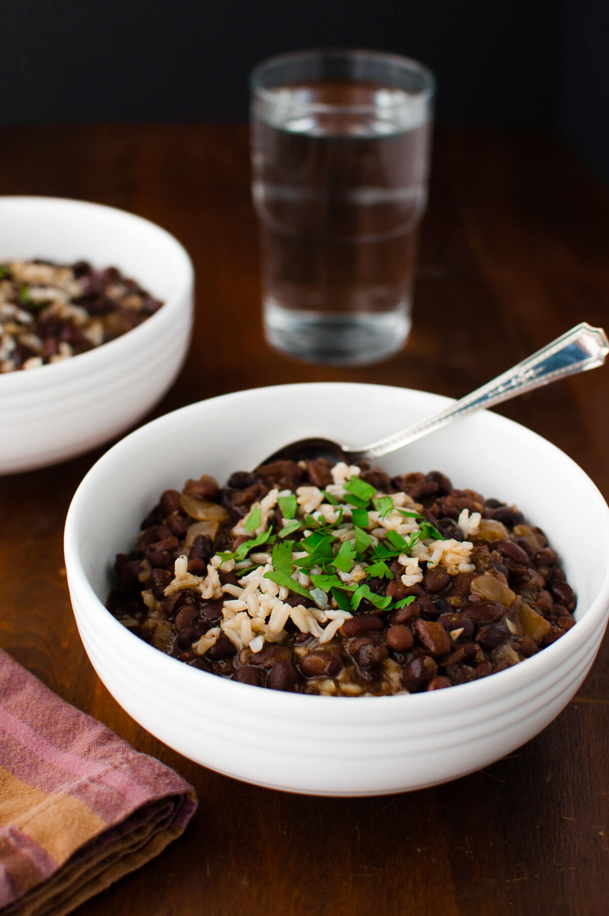 Two bowls of black bean soup with rice garnished with chopped cilantro.