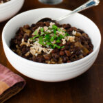 Close-up of bowl of black bean soup garnished with chopped cilantro.