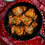 Overhead view of Moroccan chicken in a skillet on a Persian style placemat.