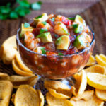 A bowl of shrimp campechana served with some frito chips.