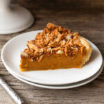 Slice of pumpkin pie on a white plate.