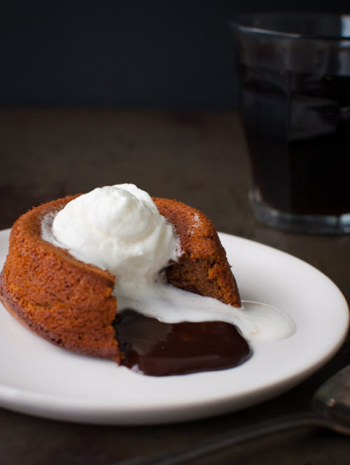 Chocolate cake with melted chocolate on the inside and topped with whipped cream.