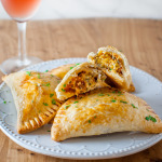 Turkey empanadas on a plate next to a glass wine.