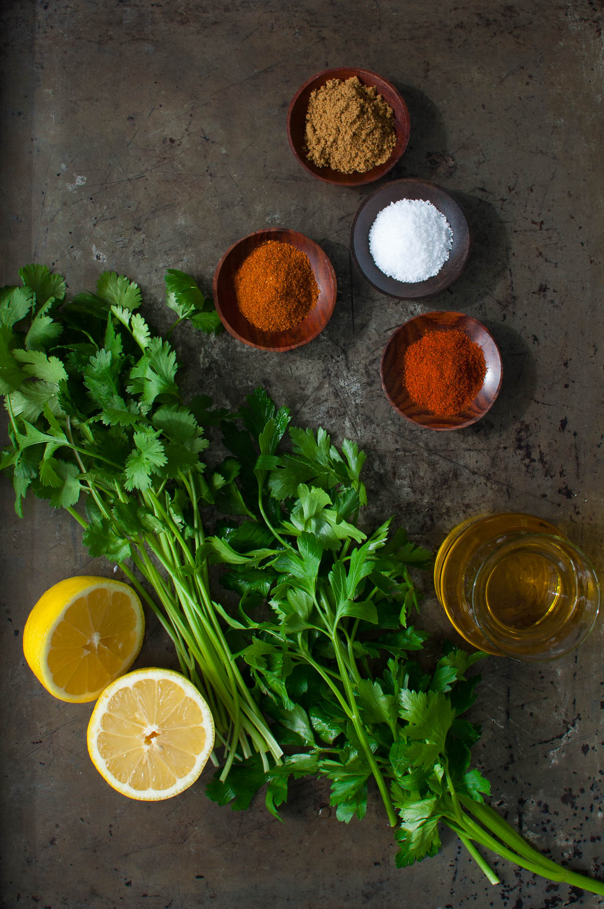 Ingredients for making chermoula sauce - spices, lemons, olive oil, parsley, and cilantro.