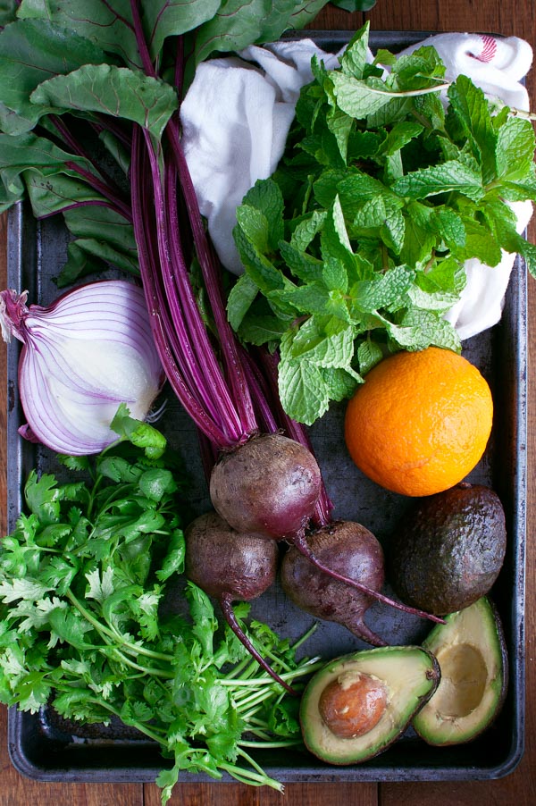 Fresh mint, cilantro, red onion, beets, and fresh avocados on a metal tray.