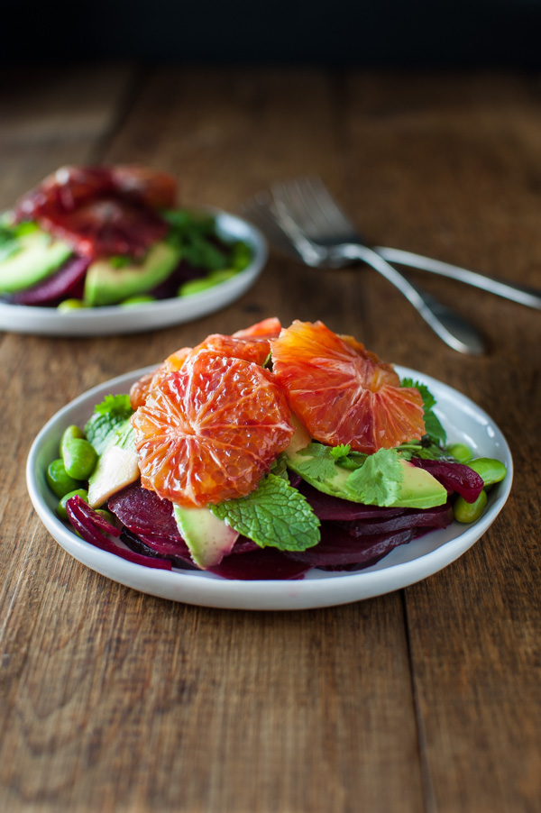 Beets, avocado, edamame, and blood orange salad on a white plate.