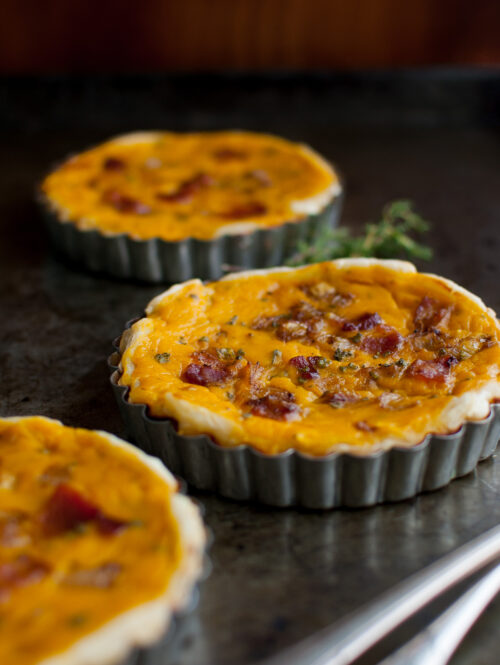 Three squash tarts on a metal tray.