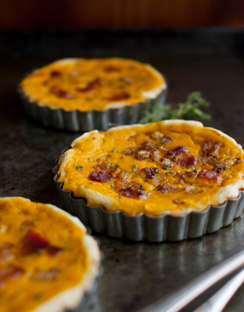 Three squash tarts on a metal tray.