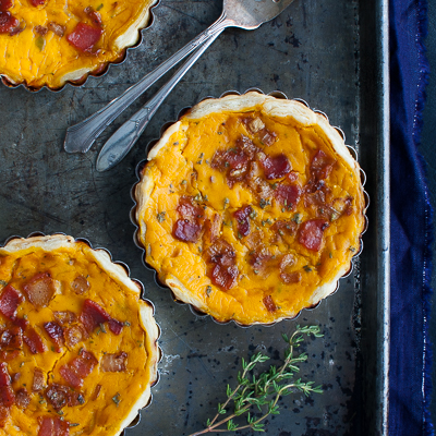 Three squash tarts and two forks on a metal tray.