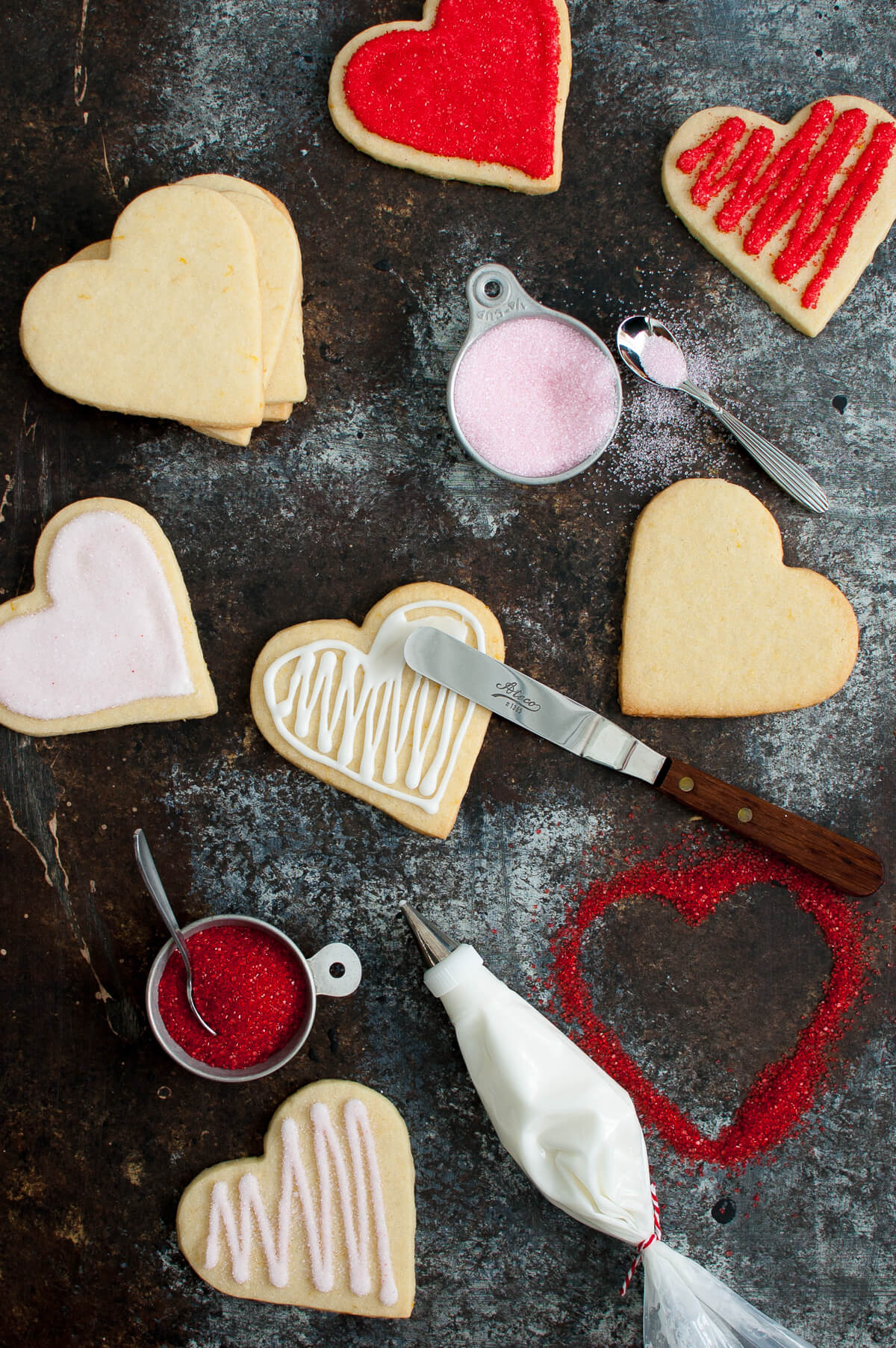 Sugar cookies on a board with icing and colored sugar for decorating.