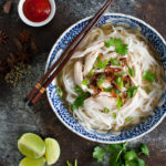 Overhead view of a bowl of chicken pho garnished with fried shallots and cilantro.