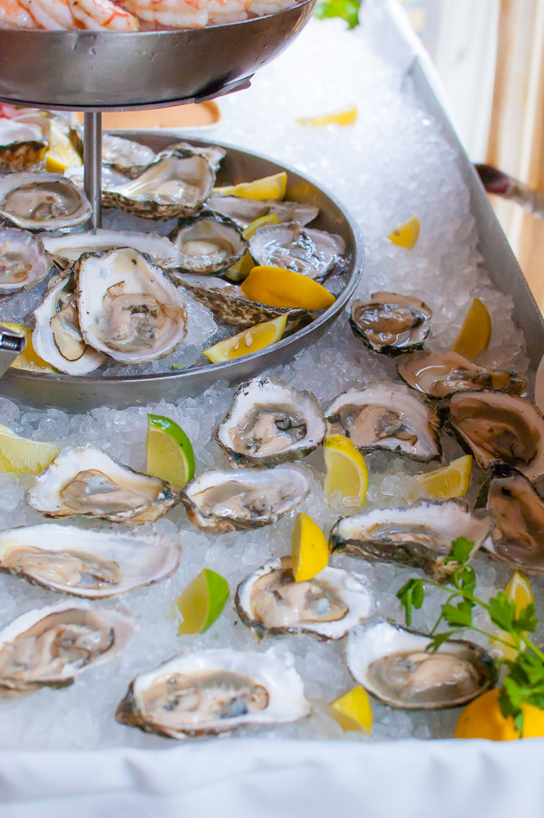 Table piled with a shucked oysters on a bed of ice.