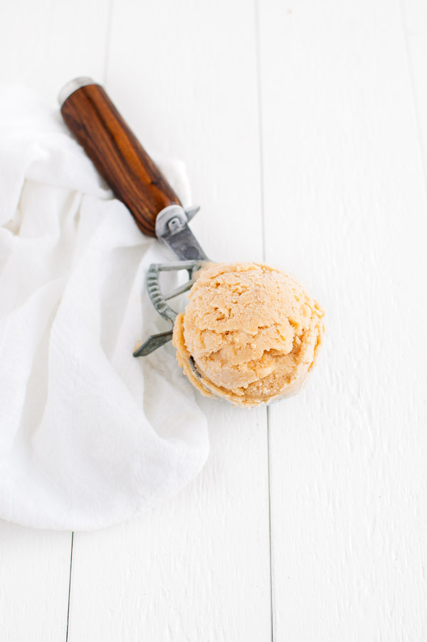 An ice-cream scoop filled with peach ice-cream.