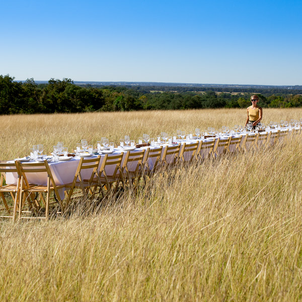 A person walking next to a long table in a field.