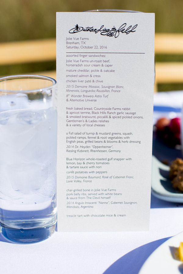 A printed menu standing next to a glass of water.