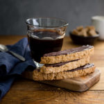 Almond biscotti and a cup of coffee on a small wooden board with a blue napkin.