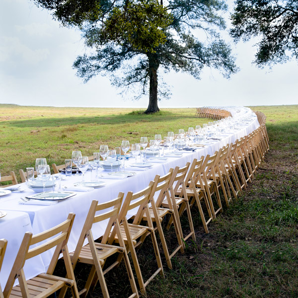 A long curved table set with plates and wine glasses.