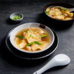 A bowl of shrimp dumpling soup topped with chopped green onions.