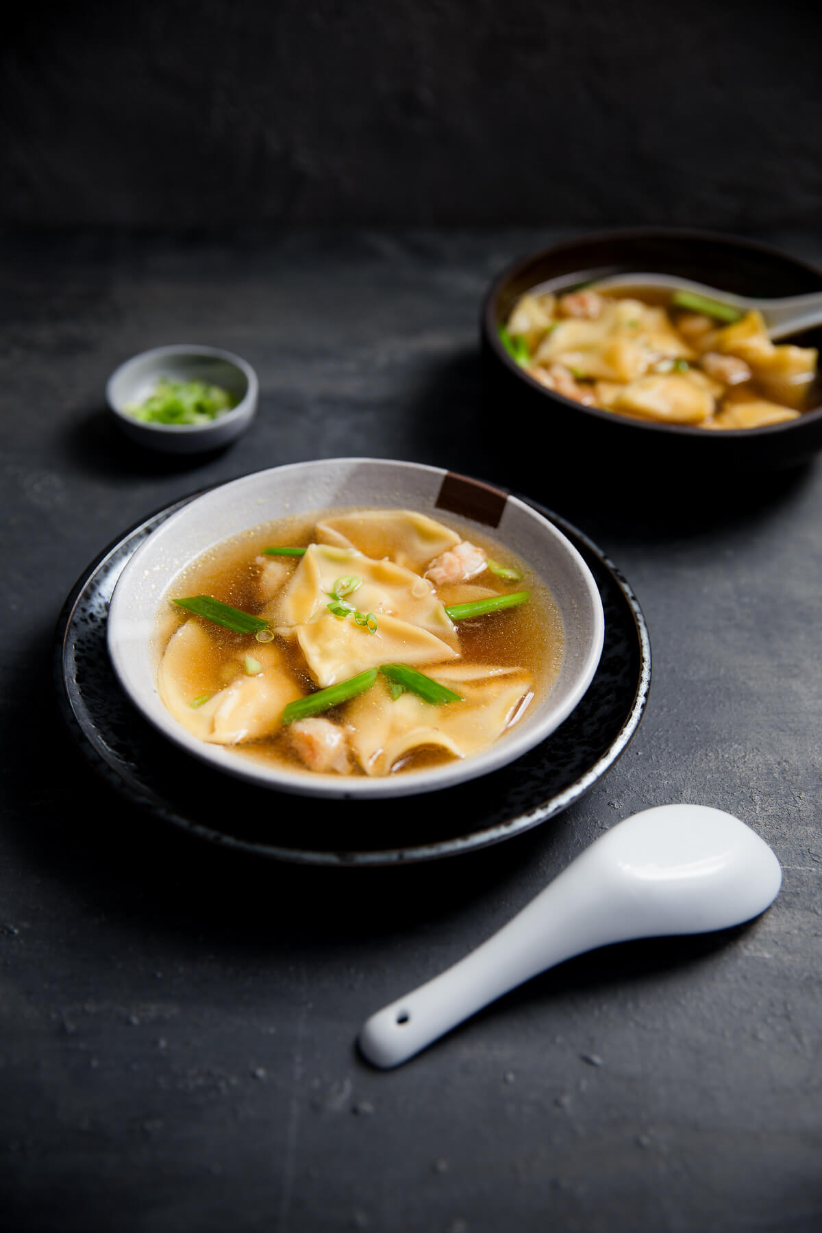 A bowl of shrimp dumpling soup topped with chopped green onions.