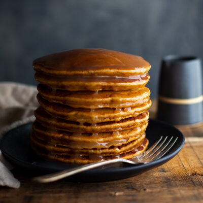A stack of gingerbread pancakes topped with lemon sauce.