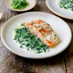 Close-up of pan seared salmon with creamed spinach on the side.