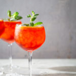 Lambrusco spritz cocktail in a wine glass and garnished with orange slices and mint sprigs.