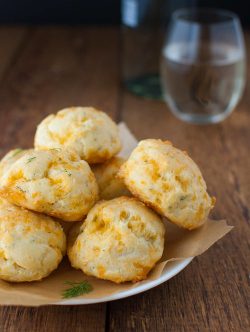 Plate of cheddar dill puffs on a wooden background.