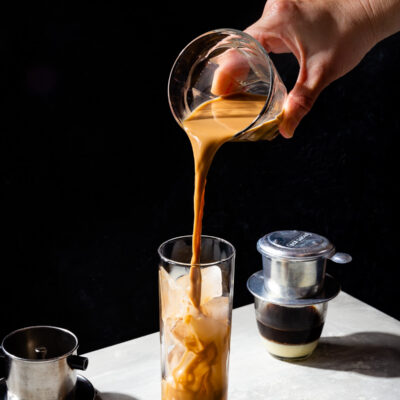 Brewed Vietnamese coffee being poured into a glass of ice.