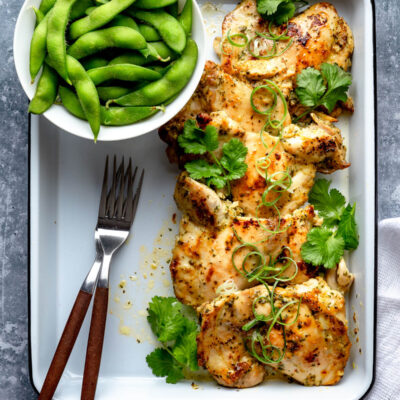 A white tray with some cilantro lime chicken and edamame.