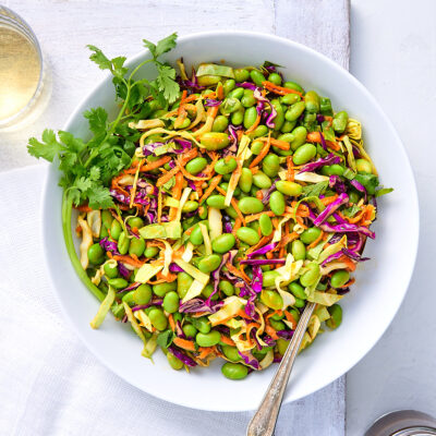 Big bowl of edamame salad with jar of miso dressing.