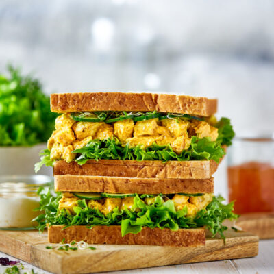 Two chicken salad sandwichs stacked on a board.