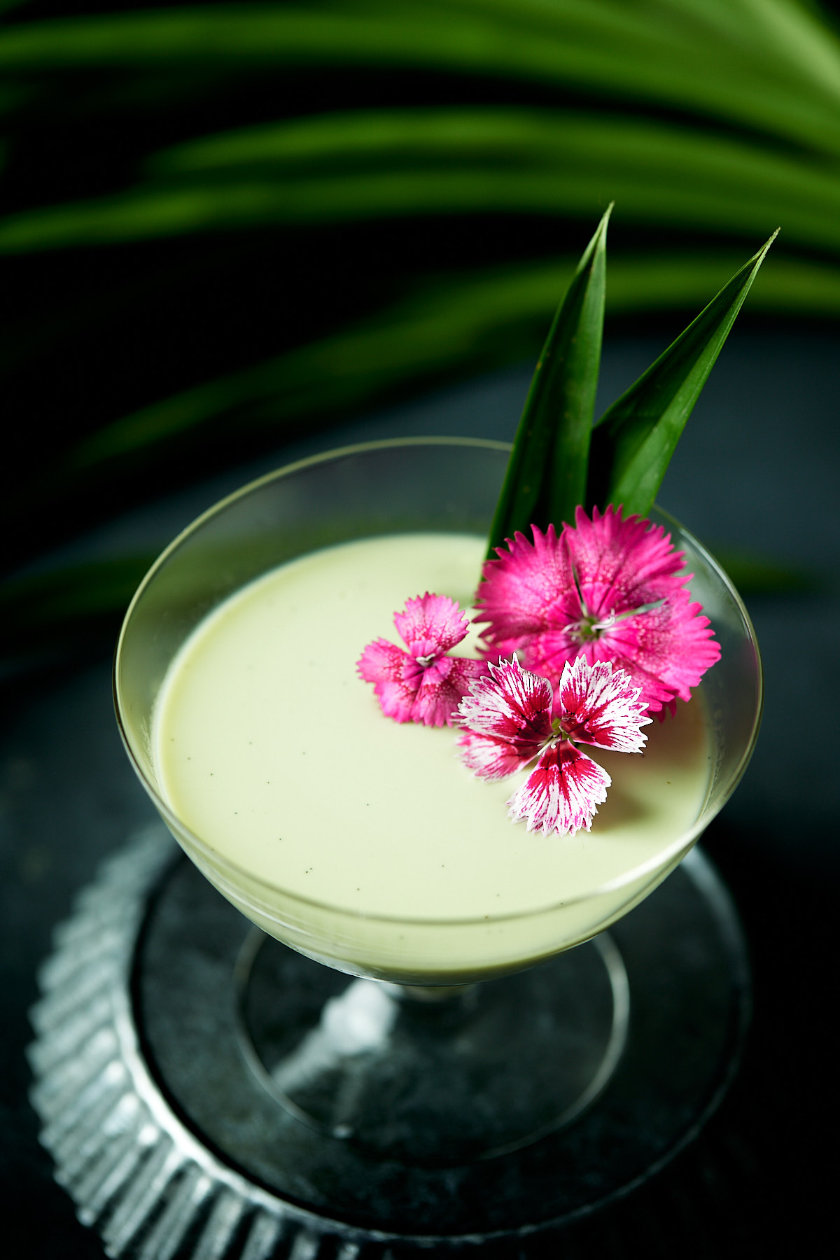 Pandan panna cotta in a glass garnished with pink flowers.