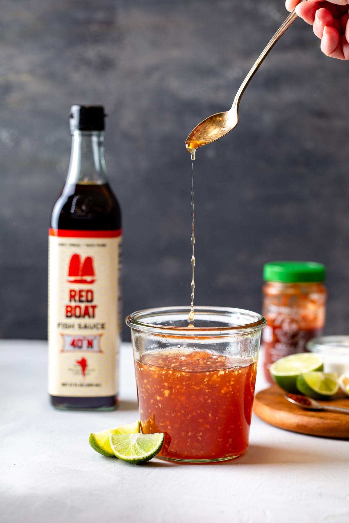 A spoon pouring some Vietnamese fish sauce into a glass jar.