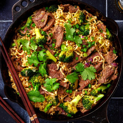 Close-up of skillet with beef noodles and broccoli.