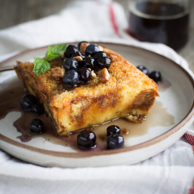 Baked brioche french toast topped with maple syrup and blueberries.