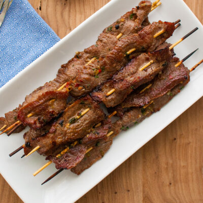 Skewers of beef satay on a white plate