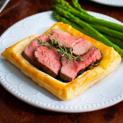 Beef Wellington tart served with asparagus.