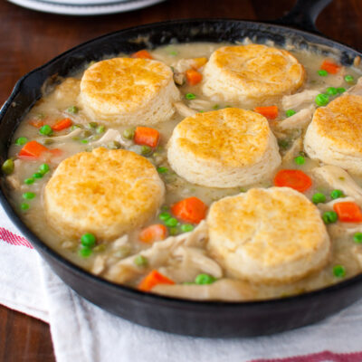 Chicken pot pie topped with biscuits in a cast iron skillet.