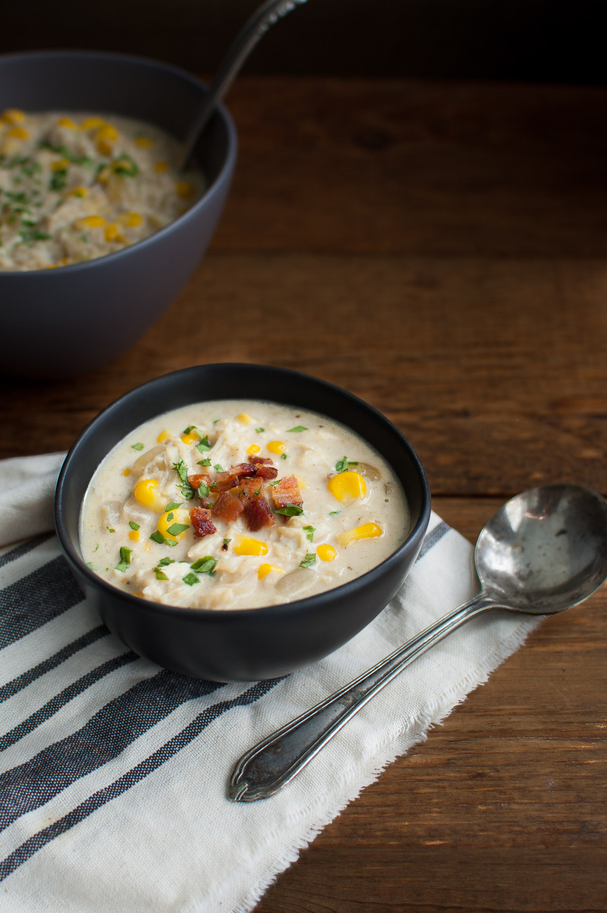 Top view of a bowl of crab and corn chowder in a black bowl.