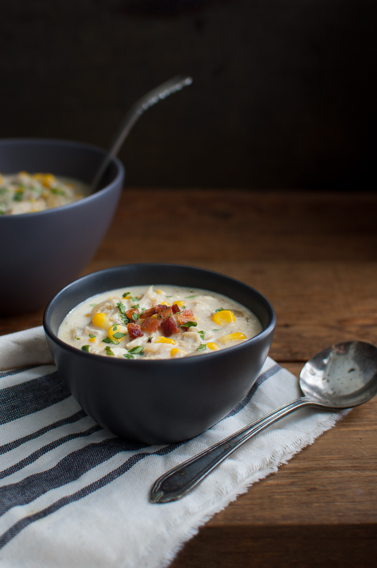 A bowl of crab and corn chowder in a black bowl.