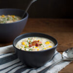 A bowl of crab and corn chowder in a black bowl.