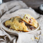 Two cranberry orange scones on a white plate with a linen napkin.