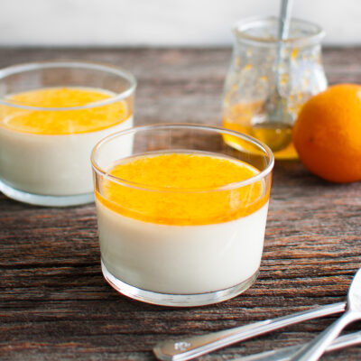 Lemon panna cotta topped with sweet meyer lemon marmalade in two glass dessert cups.