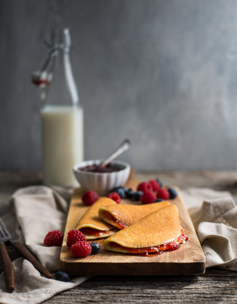 Cottage cheese pancakes on a wooden board garnished with fresh berries.