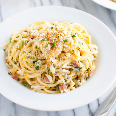 Spaghetti carbonara with crab in a white pasta bowl.