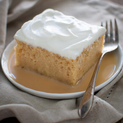 A slice of tres leches cake on a white plate.